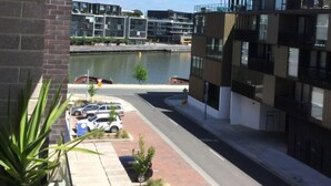 A modern building with a parking lot and a body of water in the background. - Self-contained one bedroom apartment - Kingston Foreshore on your doorstep (Kingston)