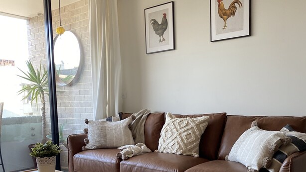 A modern living room with a brown leather sofa, a matching ottoman, and two framed rooster pictures on the wall. - Self-contained one bedroom apartment - Kingston Foreshore on your doorstep (Kingston)