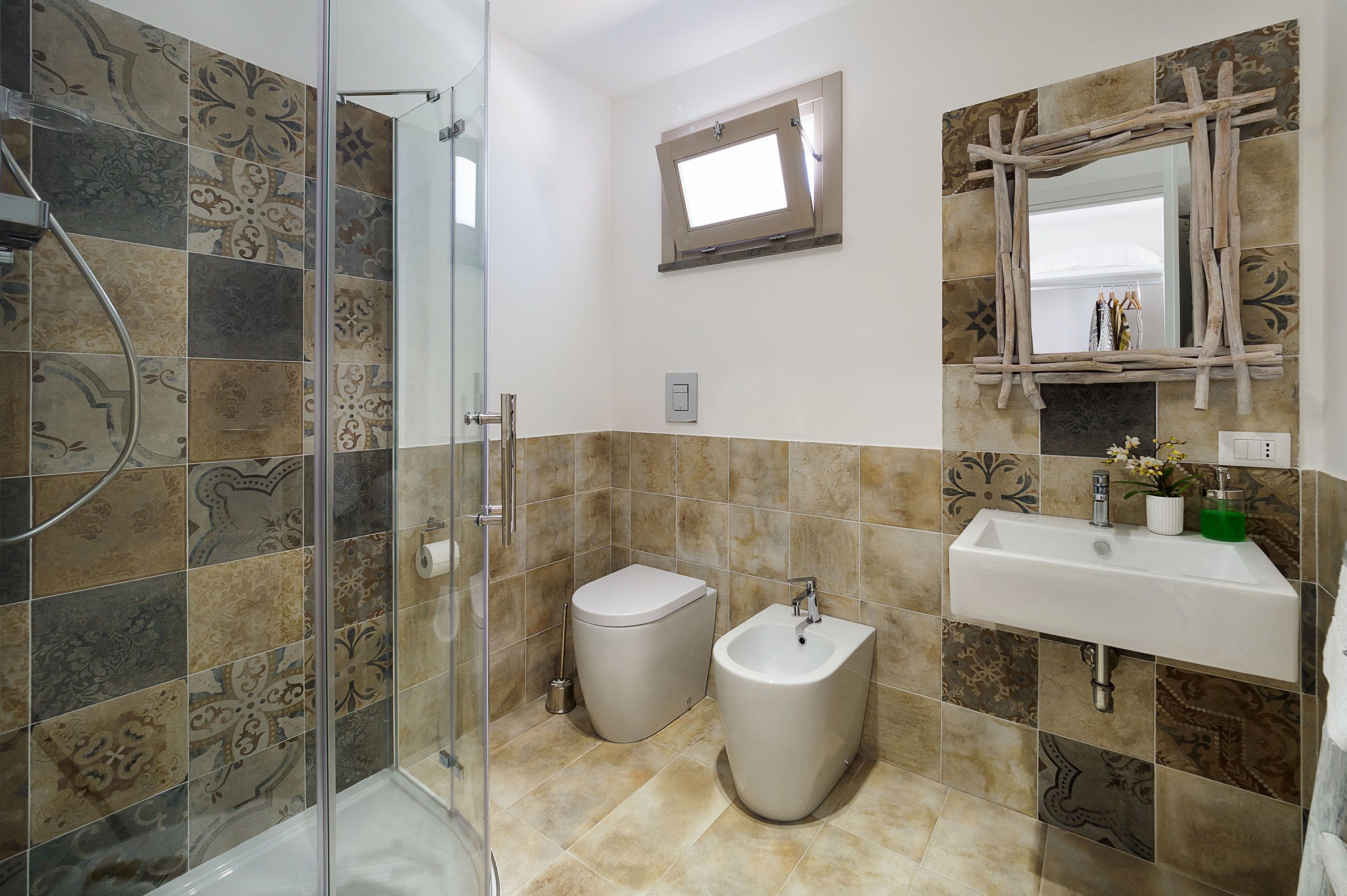 A bathroom with a shower, toilet, bidet, and sink.