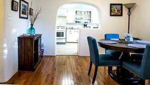 Un espace repas doté d’un plancher en bois, d’une table en bois foncé et de chaises recouvertes d’un tissu bleu.