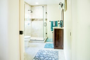 A modern bathroom with a glass-enclosed shower, a toilet, and a sink with a dark cabinet. - Downtown Santa Fe, Walk to Plaza, 2B / 2B + Full Kitchen, AIr Conditioned (Santa Fe)