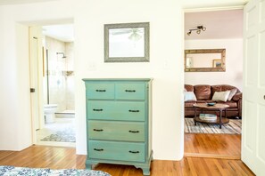 A room with a wooden floor, a teal dresser, a brown leather sofa, and a round coffee table. - Downtown Santa Fe, Walk to Plaza, 2B / 2B + Full Kitchen, AIr Conditioned (Santa Fe)