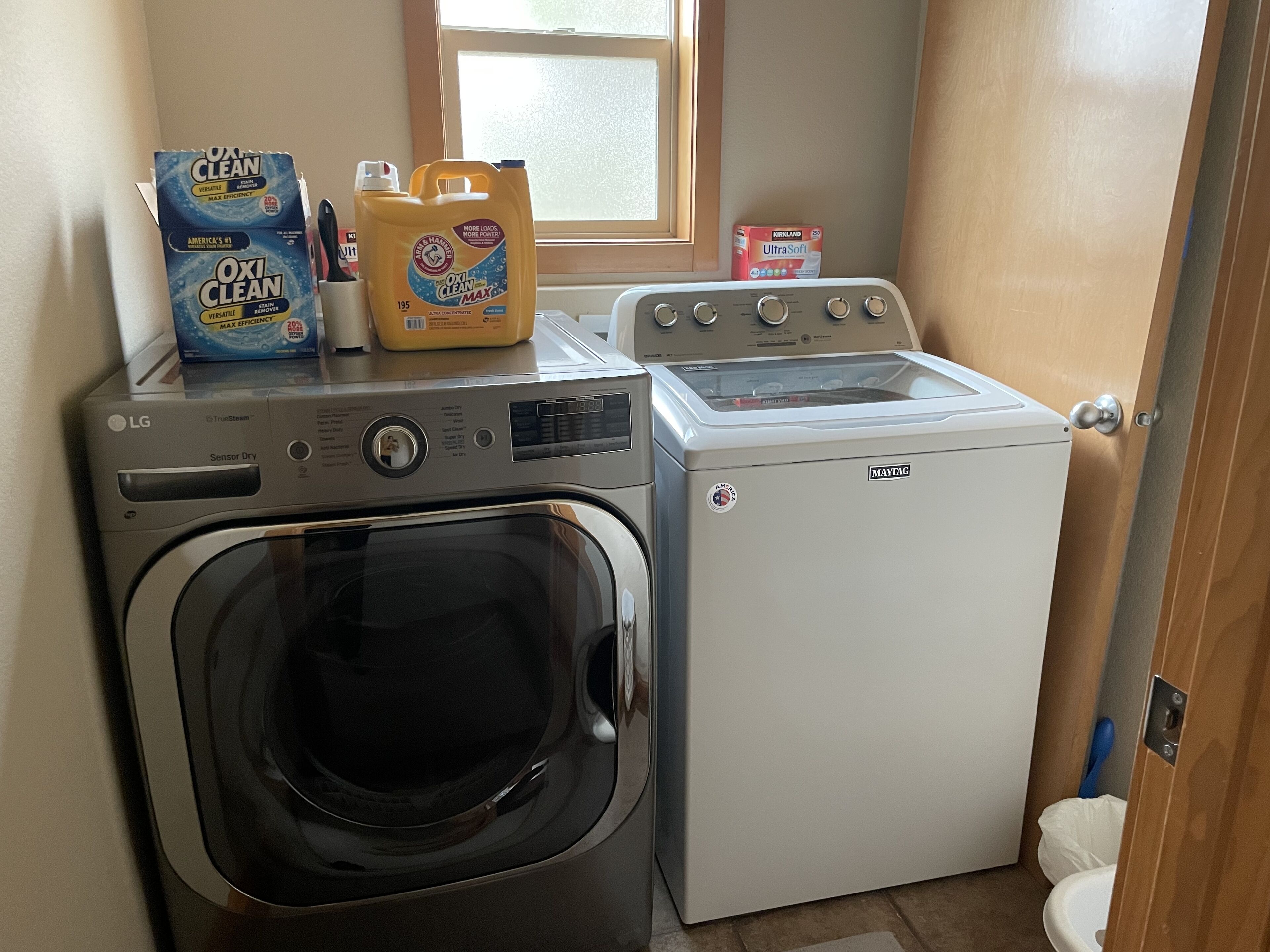 A laundry area with an LG washer and a Maytag dryer, a window, and a toilet visible in the background.