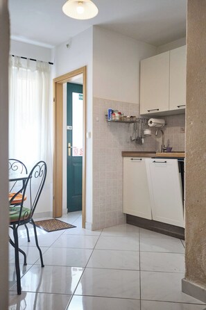 A small kitchen with white cabinets, a sink, and a window with a curtain. - Central Split Duplex – 2 min to Old Town & Riva Promenade (Split)