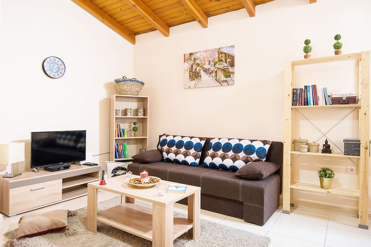 A living room with a television, sofa, coffee table, bookshelf, and decorative items.