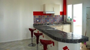 A modern kitchen with a central island, red bar stools, and a colorful backsplash. - Chic appartment with swimming pool (Tanger)