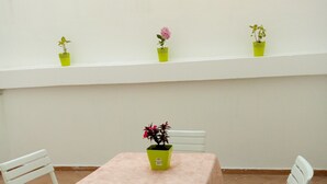 A small outdoor patio with a table and four chairs, surrounded by white walls and a window sill with potted plants. - Chic appartment with swimming pool (Tanger)