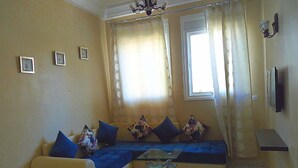 A living room with a sofa, a coffee table, and a TV. - Chic appartment with swimming pool (Tanger)