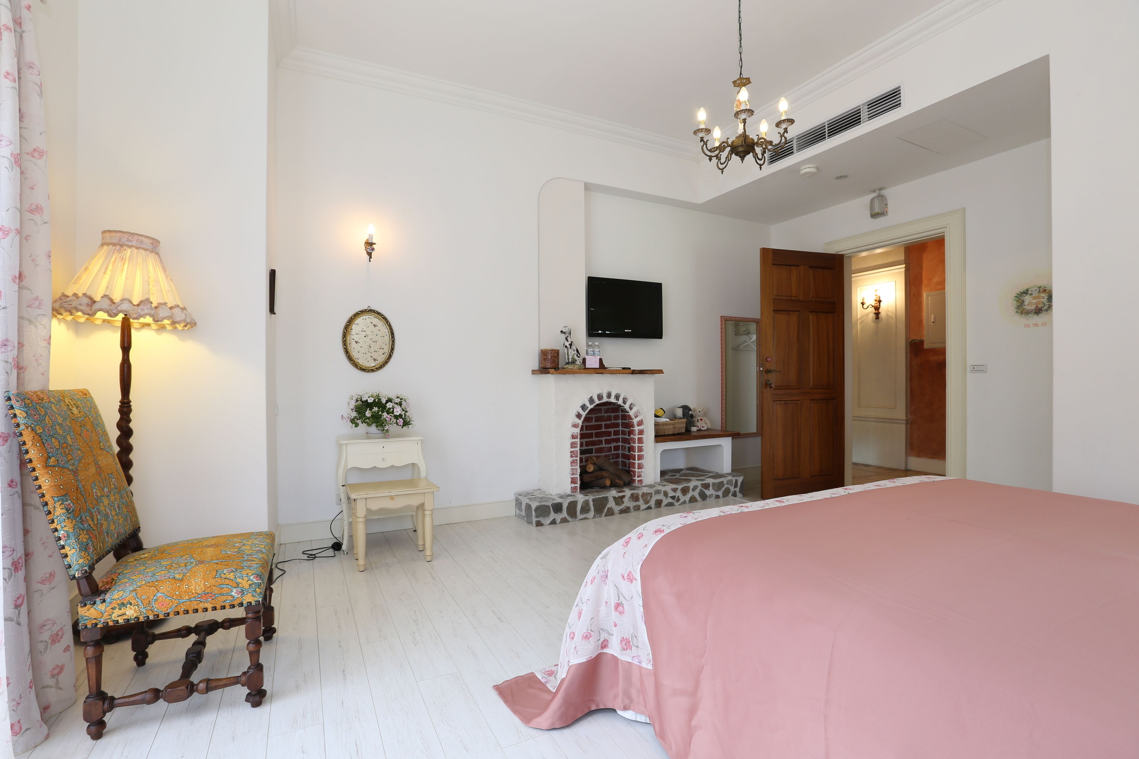 Une chambre à coucher comprenant un lit, une chaise, une télévision, une cheminée et un miroir.