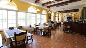 A dining area with wooden tables and chairs, large windows, and a stone fireplace. - Yun Shan Shui Villa Home (Shoufeng)
