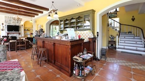 A spacious living area with a wooden bar, a stone fireplace, and a staircase leading to an upper level. - Yun Shan Shui Villa Home (Shoufeng)