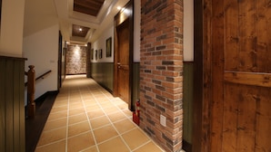 A hallway with a tiled floor, wooden doors, and a brick wall. - Yun Shan Shui Villa Home (Shoufeng)