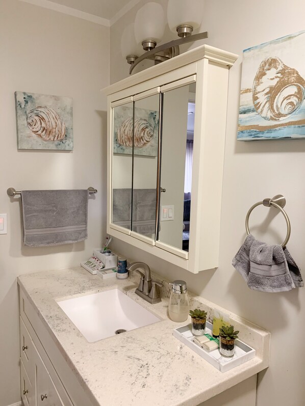 A bathroom with a large mirror, a sink, and two towels. There are two small potted plants on the sink counter. - Charming, spacious, exceptionally clean & private apt! Ideal Ithaca location! (Ithaca)