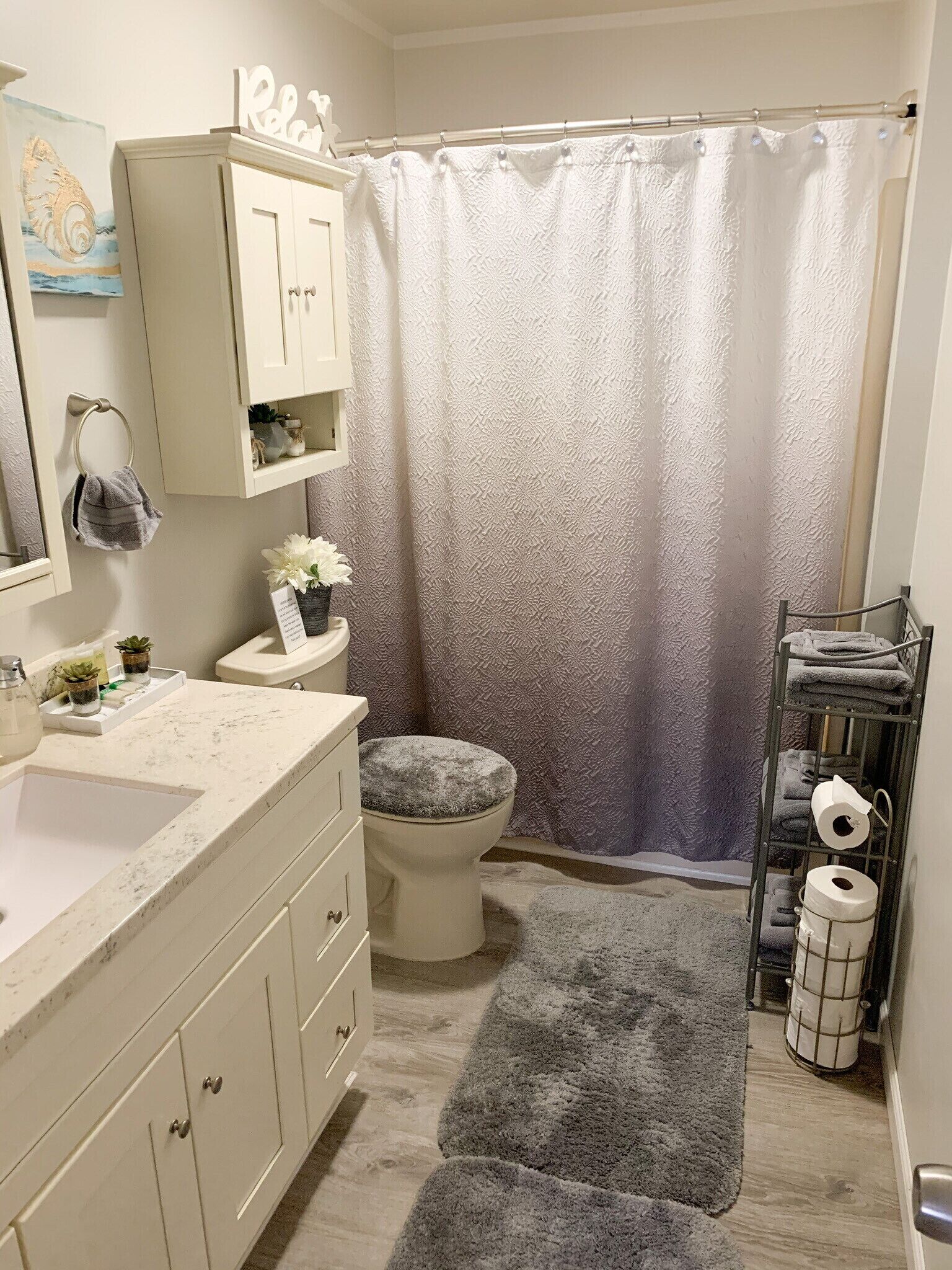 Un baño con inodoro, lavamanos, tocador y cortina de ducha.