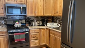 A kitchen with wooden cabinets, a stainless steel refrigerator, a microwave, and a stove. - Charming, spacious, exceptionally clean & private apt! Ideal Ithaca location! (Ithaca)