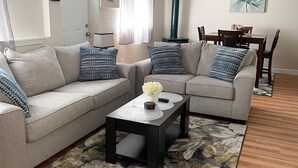 A living room with a sectional sofa, a coffee table, a dining table with chairs, and a ceiling fan. - Charming, spacious, exceptionally clean & private apt! Ideal Ithaca location! (Ithaca)