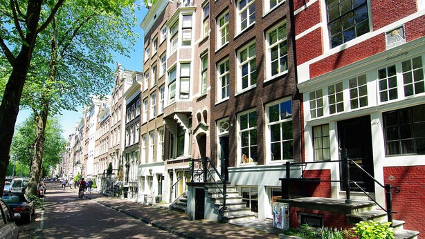 A row of traditional European-style buildings with uniform facades, a clear street, and a tree-lined sidewalk. - 1637 Historic Canal View Suites (Amsterdam)
