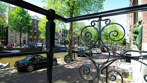 A view from a balcony overlooking a street with parked cars and buildings. - 1637 Historic Canal View Suites (Amsterdam)