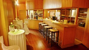 A bar area with wooden paneling, a counter with stools, and a bar stocked with glasses and bottles.