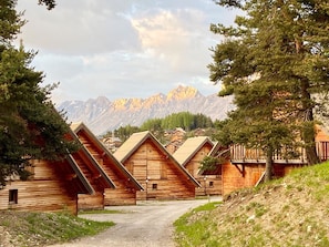 Cabañas de madera en fila, con montañas al fondo.