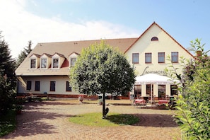 A traditional building with a tiled roof, a central tree, and outdoor seating for a restaurant.