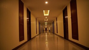 Um corredor longo e bem iluminado, com portas em ambos os lados, que dá acesso a vários quartos.