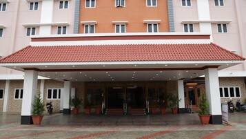 A hotel entrance with a covered walkway, potted plants, and a tiled roof.