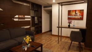 Uma sala de estar moderna com um sofá, mesa de centro e um pequeno espaço de jantar com uma cadeira e uma mesa.