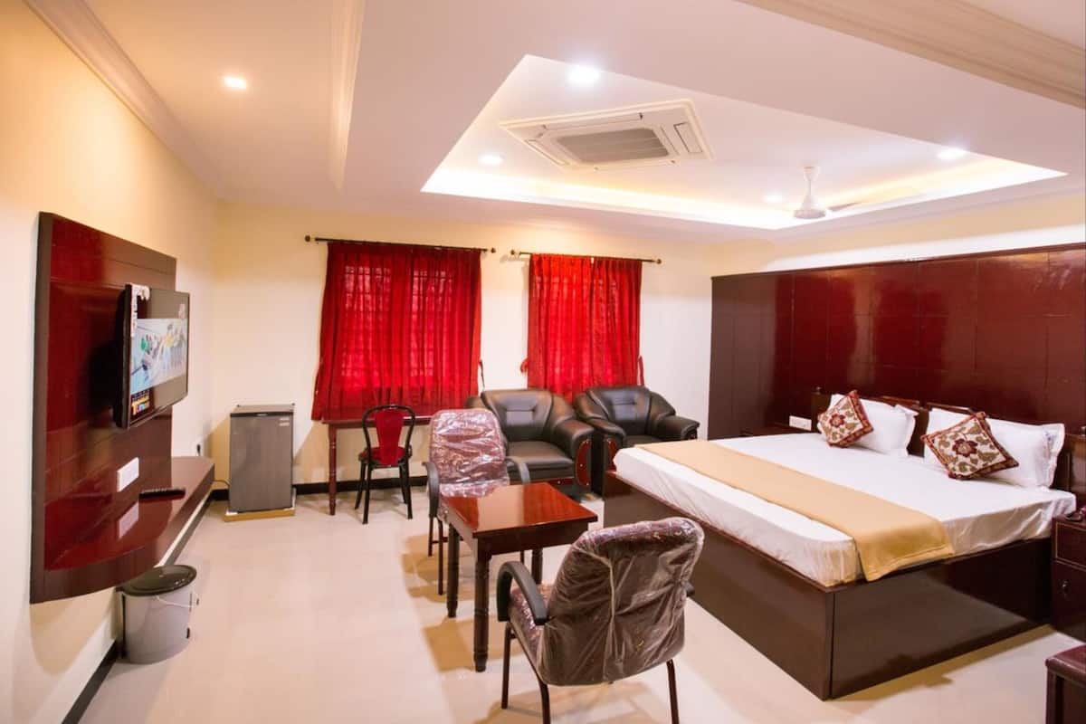 Une chambre d’hôtel avec un lit, un bureau, une chaise, une télévision et des rideaux rouges.