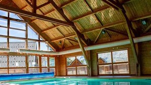A large indoor swimming pool with a high ceiling and large windows. - Semi-Detached Chalet, 3 Rooms, 7 Pers, Terrace, Free Parking, Pets Allowed (La Joue du Loup)