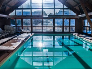 An indoor swimming pool with clear glass walls, wooden beams, and a view of snowy mountains. - Semi-Detached Chalet, 3 Rooms, 7 Pers, Terrace, Free Parking, Pets Allowed (La Joue du Loup)