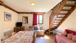 Une pièce confortable avec une table à manger, un canapé, un téléviseur et un escalier.