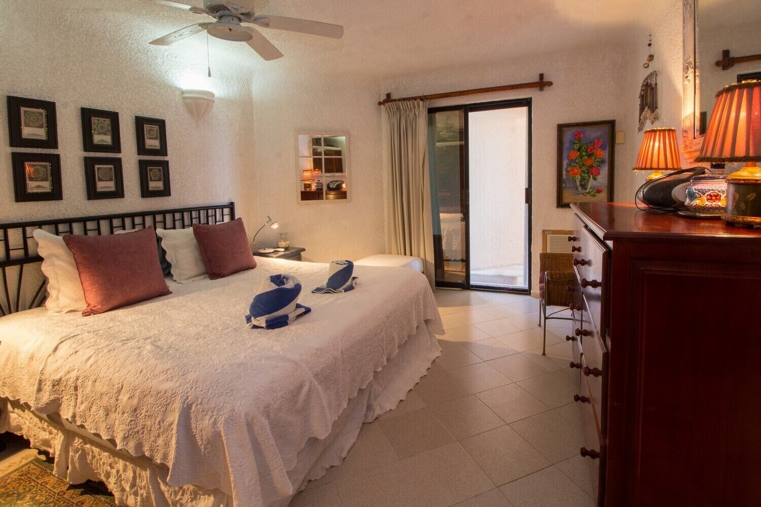 A hotel room with a bed, a desk, a chair, a lamp, and a window with curtains.