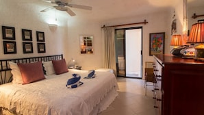 Habitación de hotel con cama, escritorio, silla, lámpara y ventana con cortinas.
