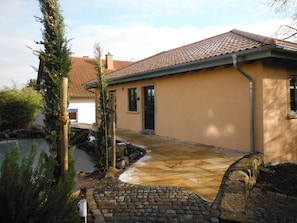 Une maison avec un toit recouvert de tuiles, une allée pavée et un chemin de pierre menant à l’entrée.