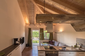 Une cuisine moderne avec un plafond en bois, une cuisinière encastrée et une grande fenêtre.