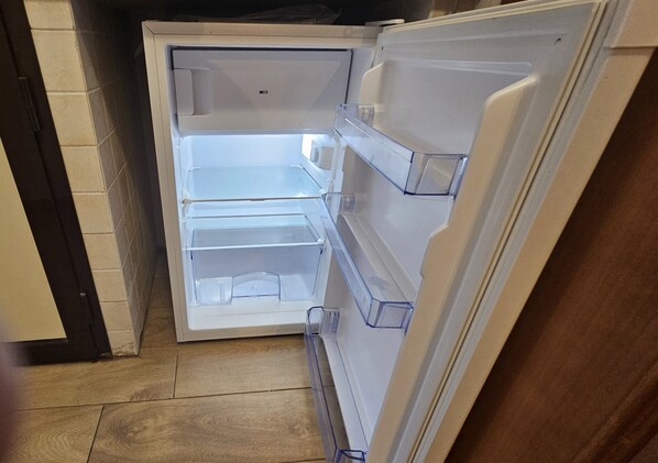 Un refrigerador abierto con varios estantes y un compartimento congelador.