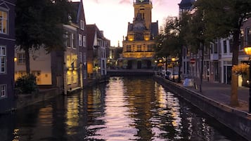 Een gracht met een historisch gebouw en een klokkentoren op de achtergrond.