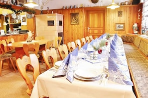 A dining area with a long table set for a meal, wooden chairs, and a bench.