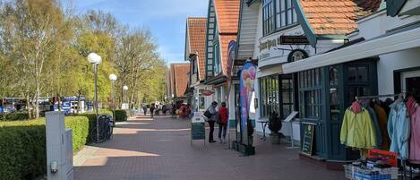 Eine Fußgängerzone gesäumt von traditionellen Gebäuden, darunter Geschäfte und Cafés.