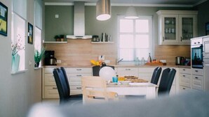 A modern kitchen with white cabinets, a wooden dining table, and black chairs. - Haus Fock - HausFock (Prerow)