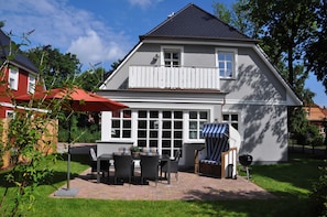 A house with a patio, a barbecue grill, and a striped umbrella. - Haus Fock - HausFock (Prerow)