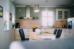 A modern kitchen with white cabinets, a wooden dining table, and black chairs.