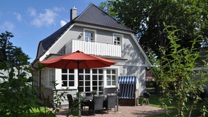 A two-story house with a balcony, a patio with a table and chairs, and a barbecue grill. - Haus Fock - HausFock (Prerow)