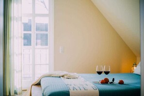 A bedroom with a bed, a window, and two glasses of red wine on the bed. - Haus Fock - HausFock (Prerow)