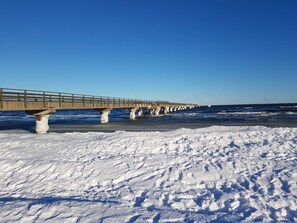 A pier extending into a snowy beach with clear skies.