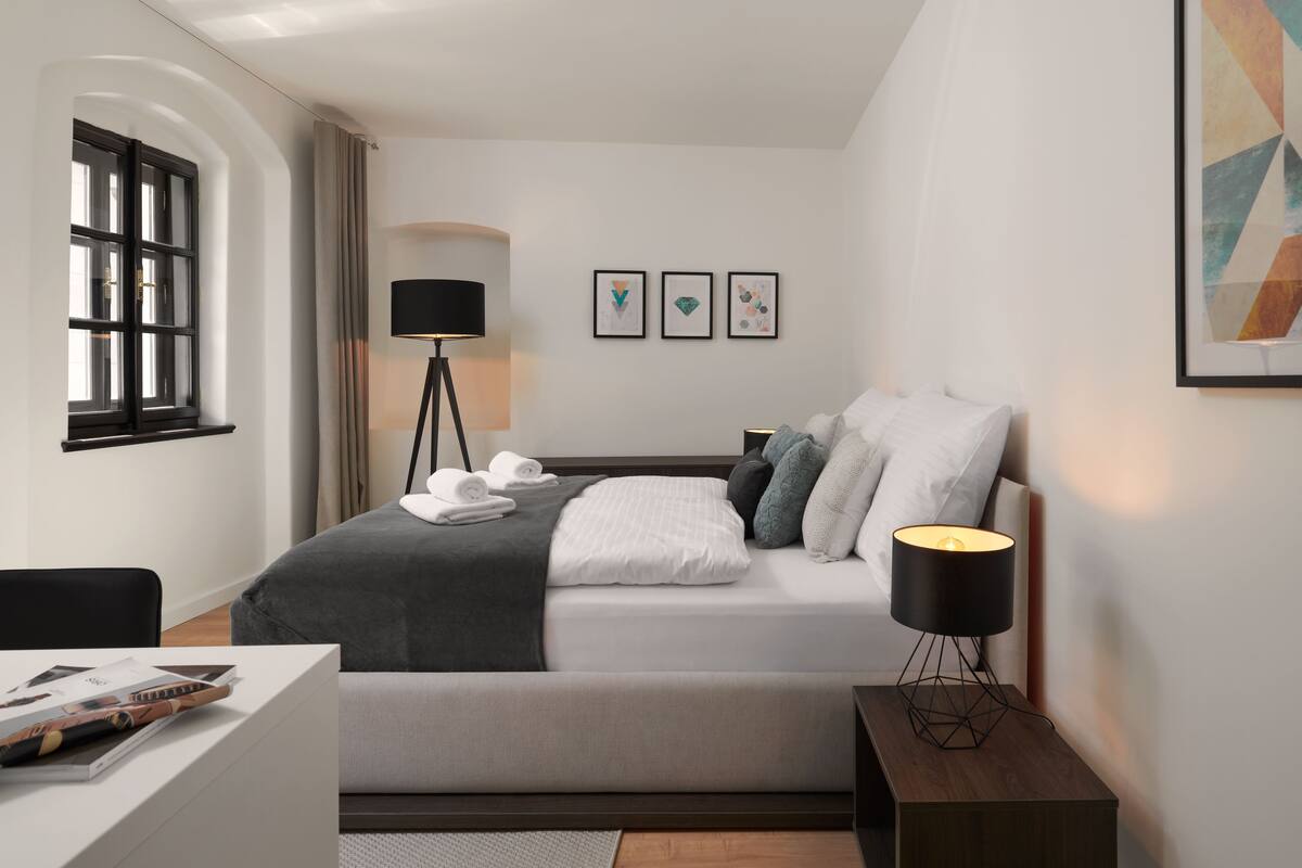 A modern bedroom with a bed, bedside lamp, and artwork on the wall.