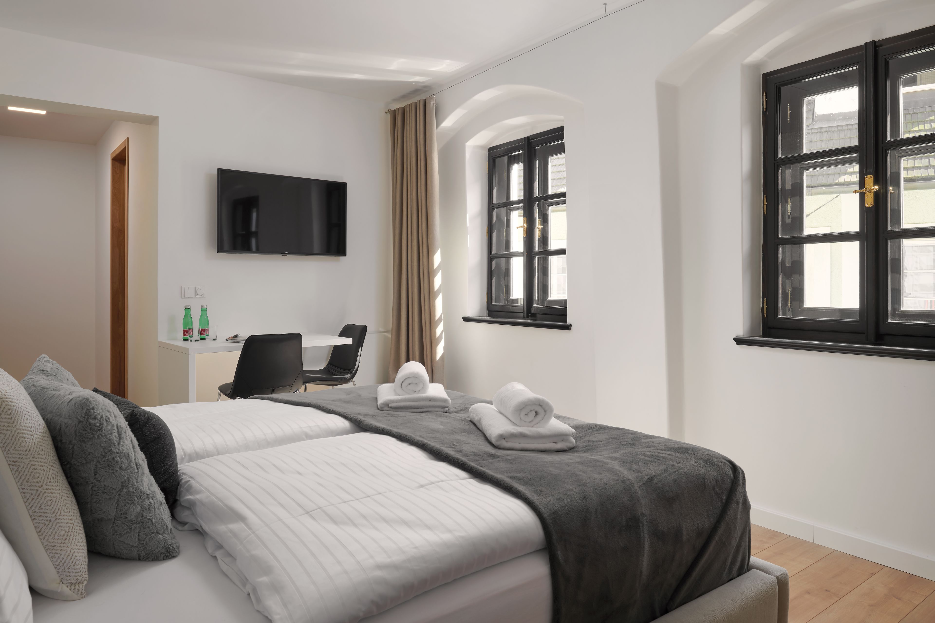 A hotel room with a bed, a desk, a chair, a TV, and a window.