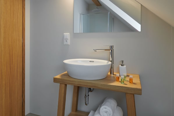 Un baño moderno con un lavamanos blanco, tocador de madera y un espejo encima.