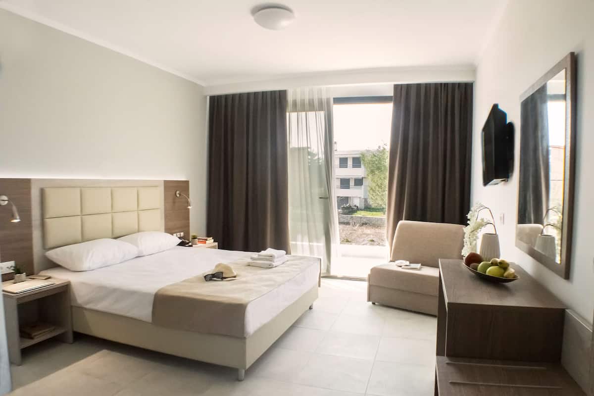 Una habitación de hotel moderna con una cama grande, un escritorio, una silla y un balcón con cortinas.